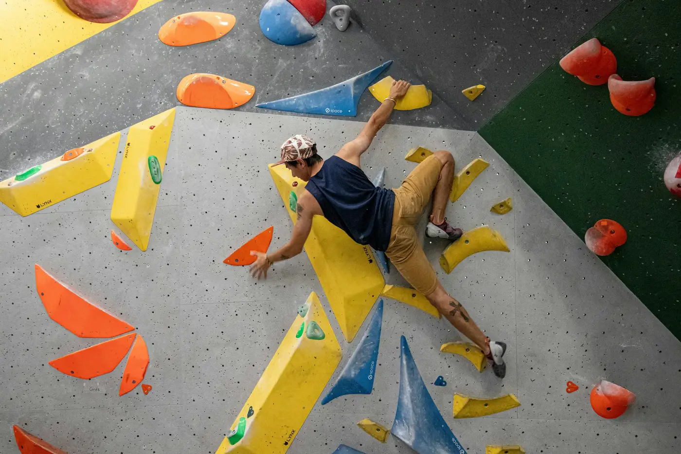 Klimmer reikt naar een greep op een overhangende boulder